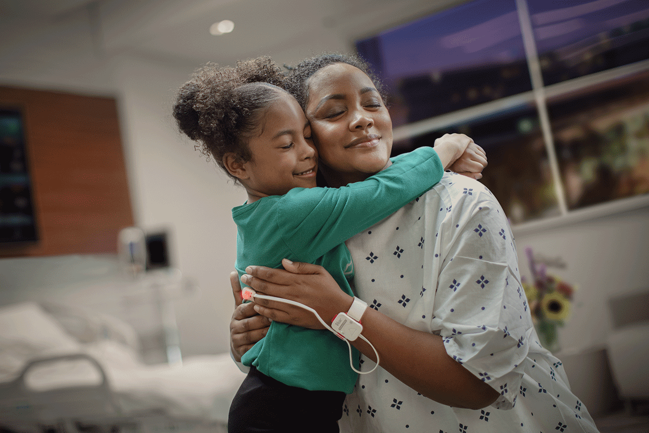 Jeune femme assise sur un lit qui porte un capteur Opioid Halo et qui vérifie son application pour téléphone intelligent